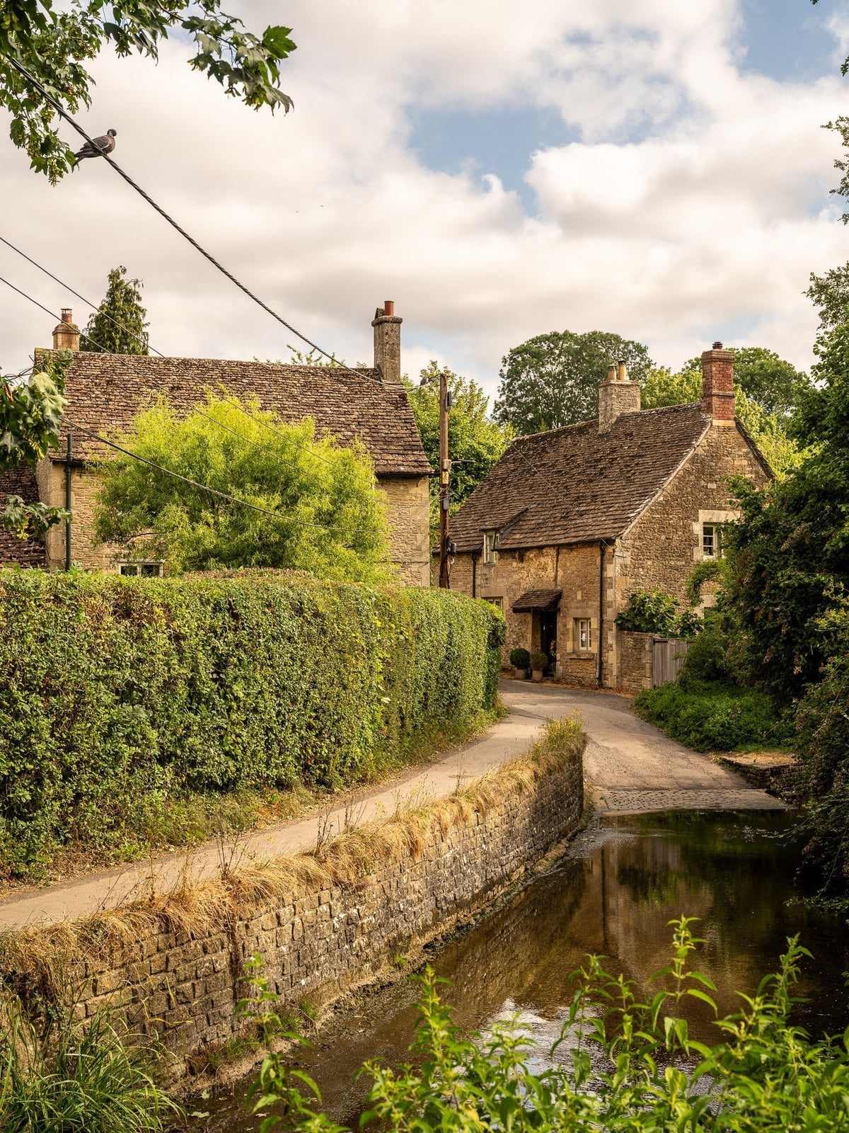 Footpath alongside a stream and cottage in Lacock, a Cotswolds village